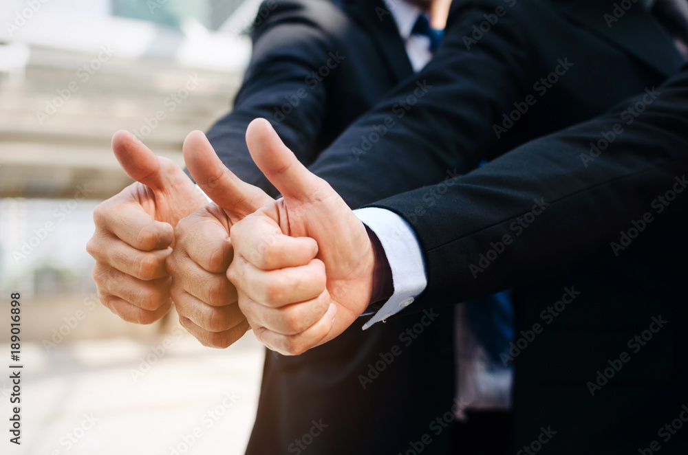 Fototapeta premium close up of hand group of handsome business people team in suit showing thumbs up as like sign together in the city, successful, support, meeting, partner, teamwork, community and connection concept