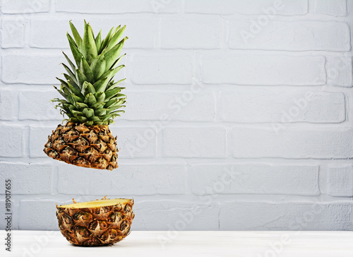 Fresh ripe flying cut juicy pineapple on gray brick wall background