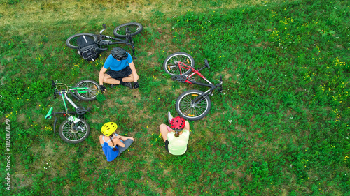 Family cycling on bikes outdoors aerial view from above, happy active parents with child have fun and relax on grass, family sport and fitness on weekend 