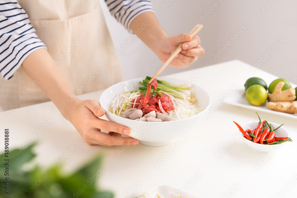 Female chef prepare traditional Vietnamese soup Pho bo with herbs, meat, rice noodles Female chef prepare traditional Vietnamese soup Pho bo with herbs, meat, rice noodles