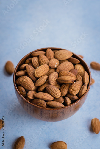 Almonds in brown bowl on blue sone concrete background. Copy space