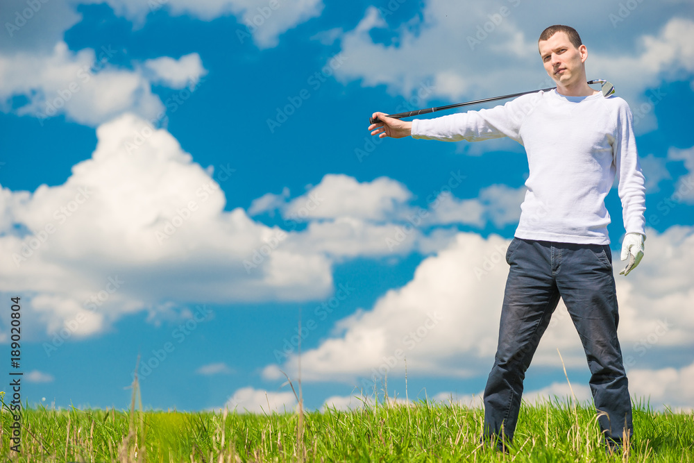 in the green field a successful golfer posing with a golf club on a sunny day in the green field a successful golfer posing with a golf club on a sunny day