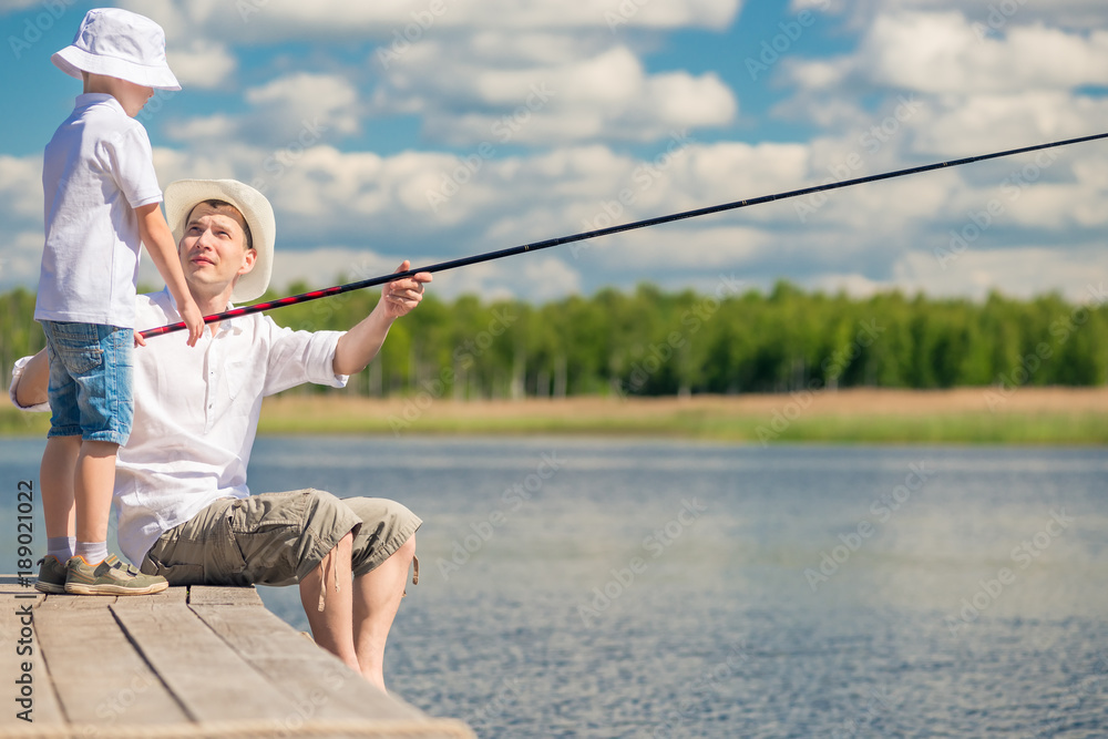 fishermen father and son on the pier fish in the lake fishermen father and son on the pier fish in the lake