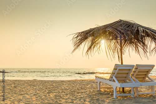 Fototapeta Naklejka Na Ścianę i Meble -  empty chairs under thatched umbrellas on a sandy beach. Tinted.