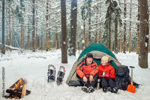 a couple on an expedition in the winter mountains and the forest, a break for tea photo