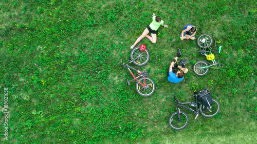 Family cycling on bikes outdoors aerial view from above, happy active parents with child have fun and relax on grass, family sport and fitness on weekend 