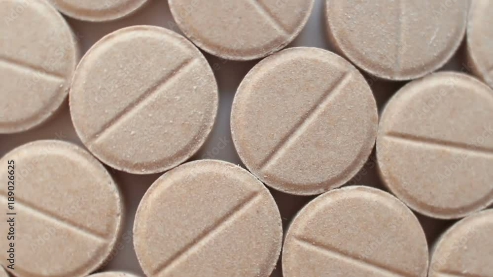 Many brown pills rotate on a plate Many brown pills rotate on a plate