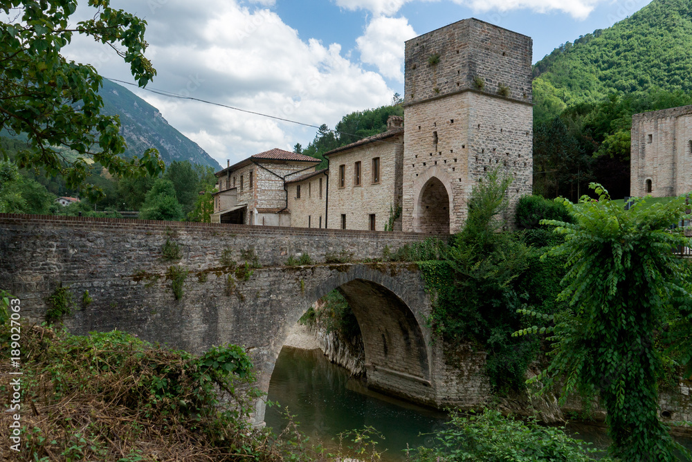 Medieval village with stone bridge over a river. Genga, Italy