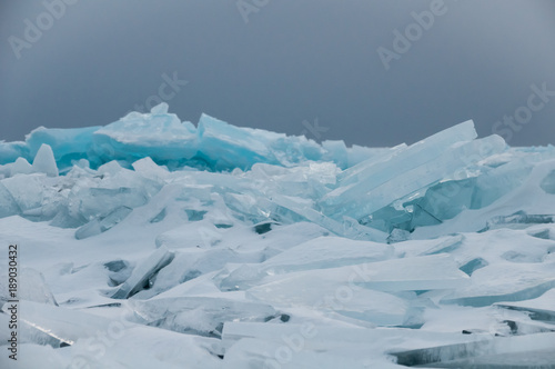 dawn in the blue hummocks of ice lake baikal, in a snowy field in winter on a journey © Baikal360