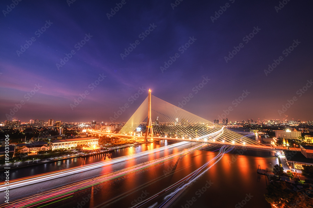 Fototapeta premium King Rama 8 bridge famous transportation facility in bangkok during night time and light from boat under bridge