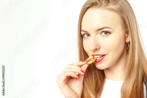 Business woman tasting golden bitcoin by her tooth