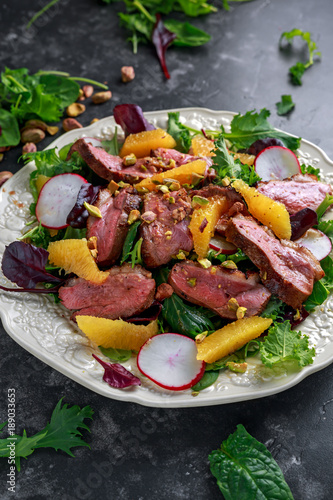 Duck breast fillets steak salad with orange halves, radishes and crushed pistachios