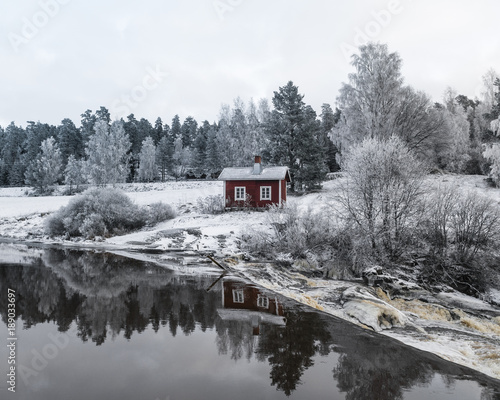 Winter landscape. red cottage next to river. © tommitt