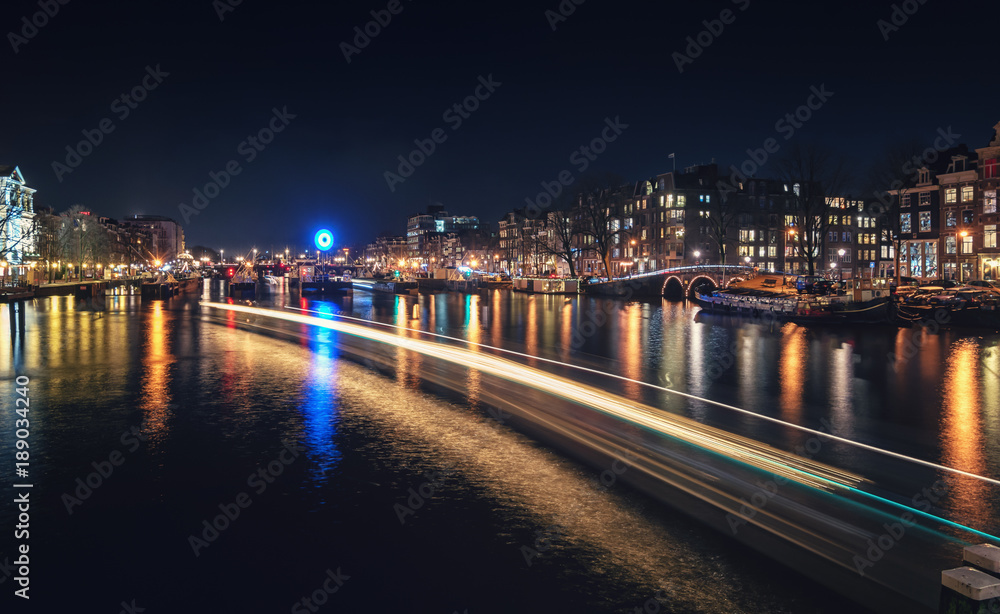 Fototapeta premium The lock in the river Amstel with the characteristic canal houses along the river in the old center of Amsterdam.