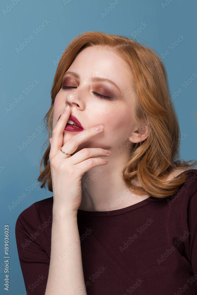 Close up shot of stylish young woman against blue background. Redhead girl with closed eyes. makeup, Spa.