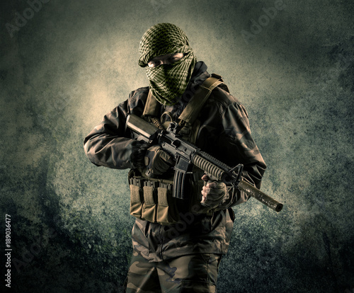 Portrait of a heavily armed masked soldier with grungy background photo