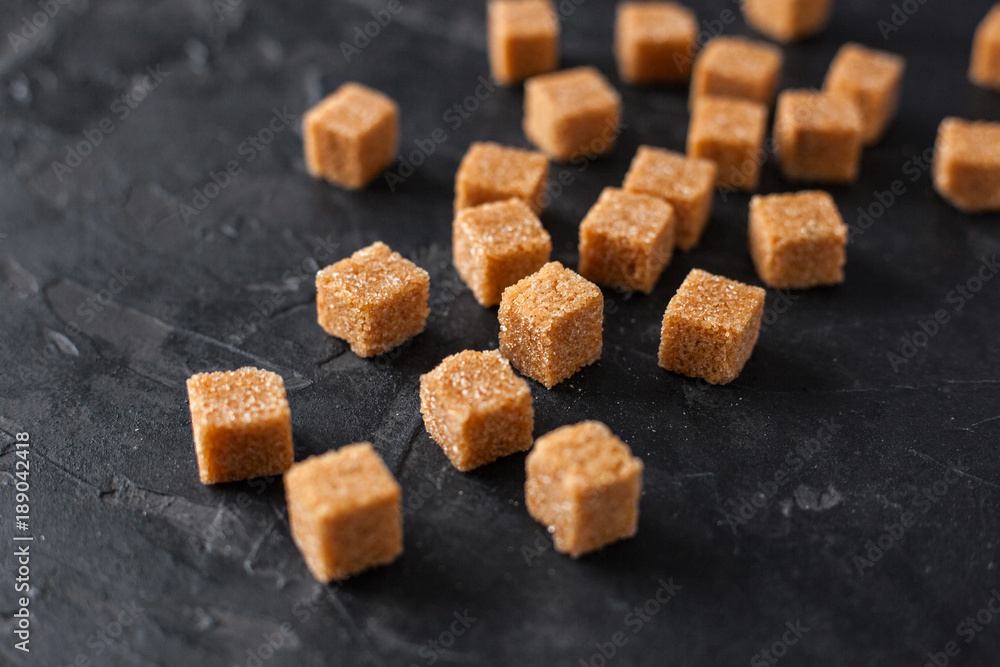 Brown cane sugar cubes pile on a black background Brown cane sugar cubes pile on a black background