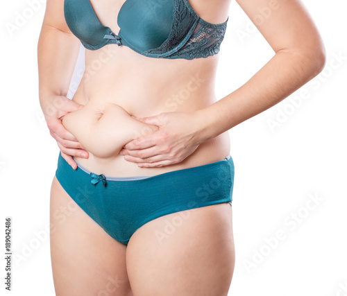 Girl with a little overweight. Young girl isolated on white background showing fat on stomach © adragan