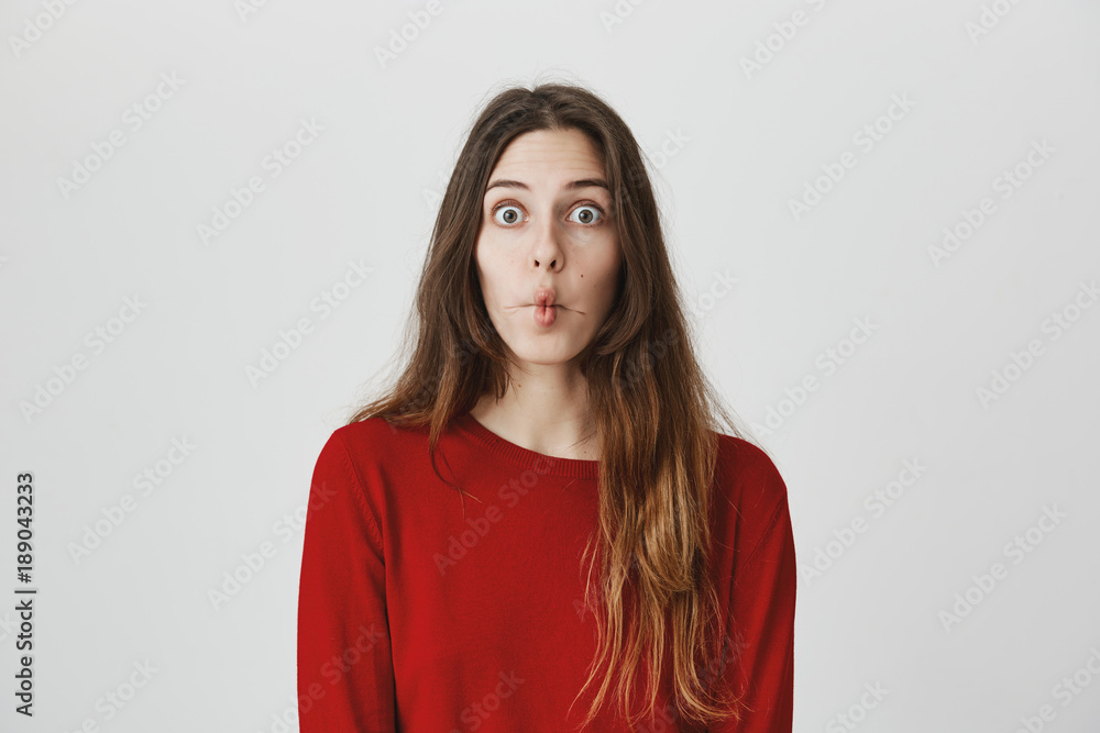 Funny young girl with popped eyes imitating fish, folding her lips and popping eyes, isolated over white background. Model fools around being childish and cute. Funny young girl with popped eyes imitating fish, folding her lips and popping eyes, isolated over white background. Model fools around being childish and cute.