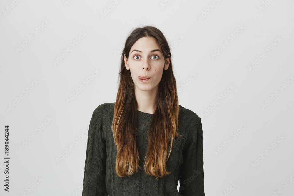 Naughty european girl with dark hair in green sweater misbehaving, sticking out her tongue at camera as a sign of disobedience, protest and disrespect. Emotions, reactions, feelings and attitude Naughty european girl with dark hair in green sweater misbehaving, sticking out her tongue at camera as a sign of disobedience, protest and disrespect. Emotions, reactions, feelings and attitude