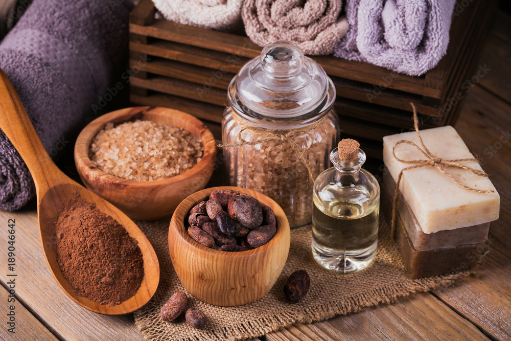 Natural cosmetic oil, sea salt and natural handmade soap with cocoa beans on rustic wooden background Natural cosmetic oil, sea salt and natural handmade soap with cocoa beans on rustic wooden background