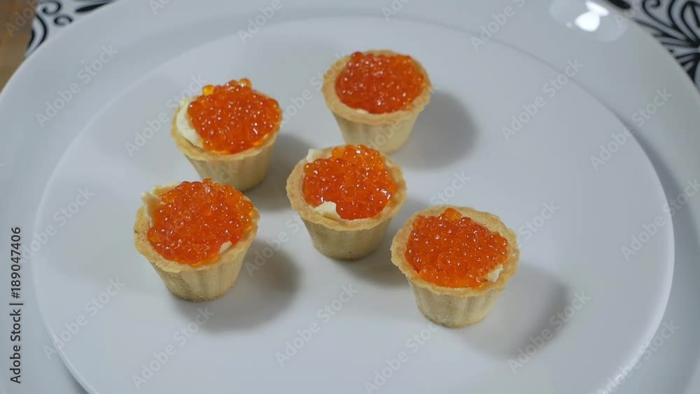 Taking a tartlet snack with red caviar and butter Taking a tartlet snack with red caviar and butter