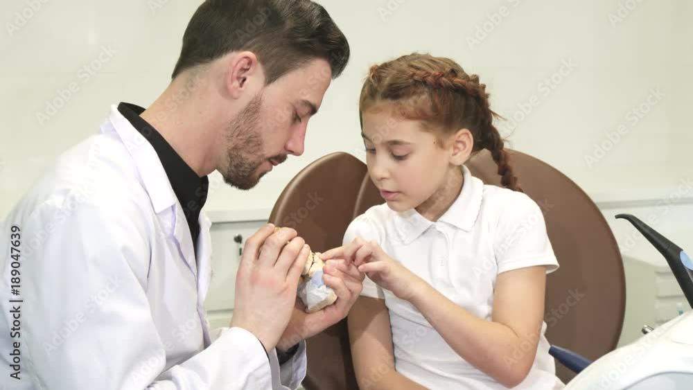 A smart doctor tells a little girl about the structure of the human jaw A smart doctor tells a little girl about the structure of the human jaw