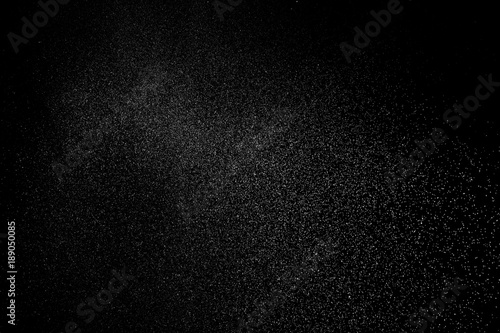 Freeze motion of white particles on black background. White granule explosion. Abstract white dust overlay texture.