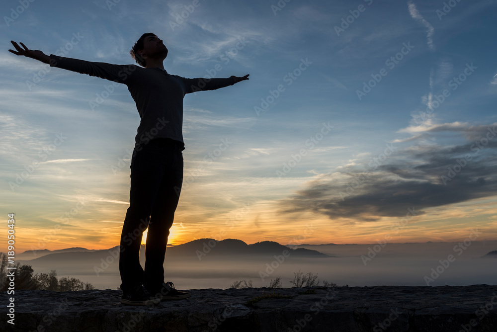 Man in casual clothes with his arms spread widely standing outdoors