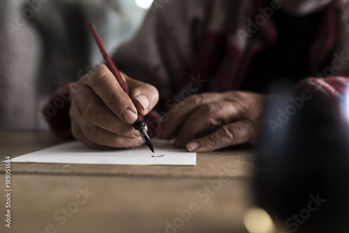 A man with dirty hands writing on a sheet of paper