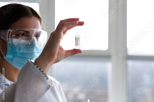 Woman laboratorian holding antibiotics samples and syringe photo