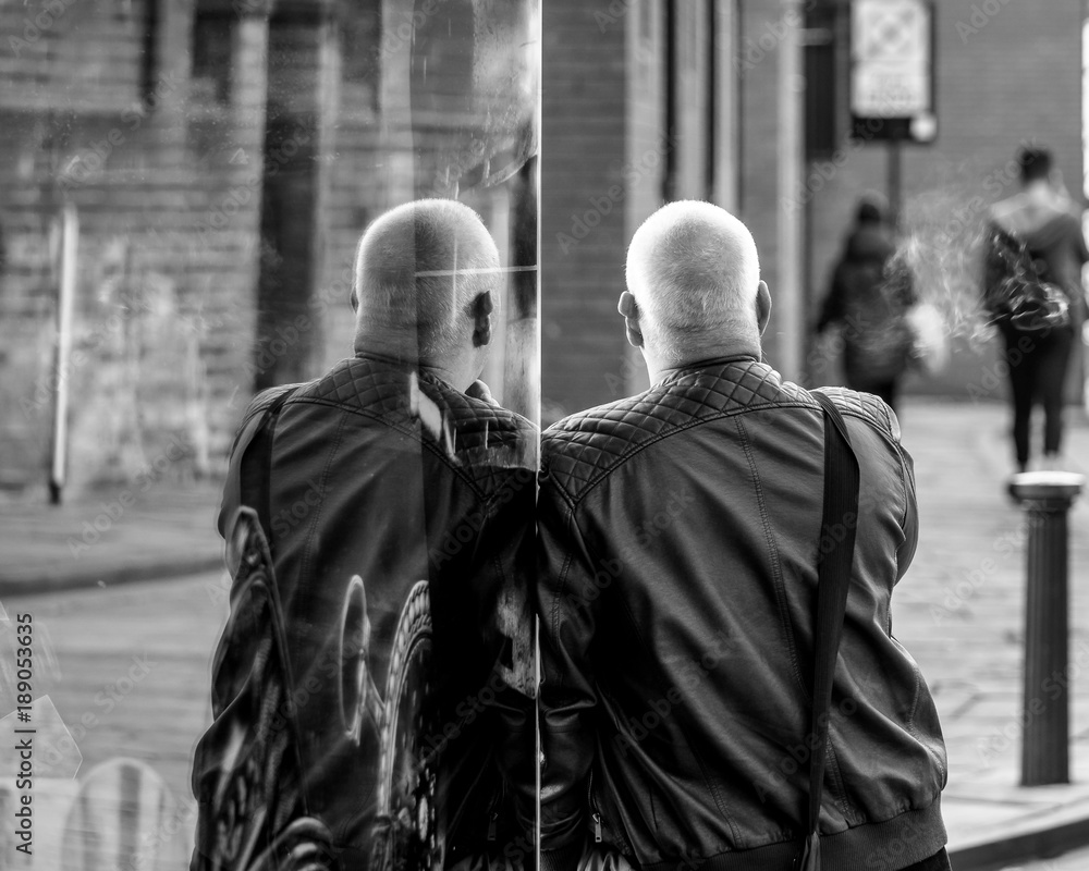 Man Leaning Against Shop Window Which Shows His Reflection, Black and White Street Photography, Shallow Depth of Field