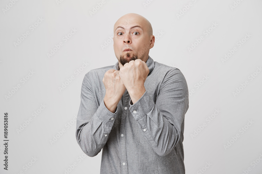 Adult bearded man with weard expression ready to fight holding his fists up over white background. Person tries to act confident but looks afraid. He wanted to avoid any conflict. Adult bearded man with weard expression ready to fight holding his fists up over white background. Person tries to act confident but looks afraid. He wanted to avoid any conflict.