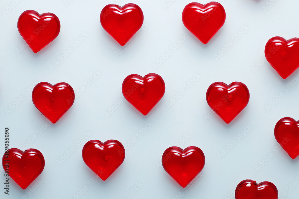 Red small shiny hearts on a white background. Spread apart