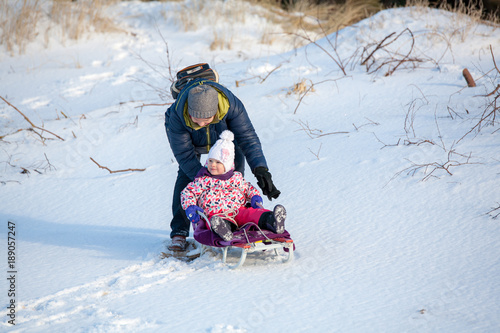 Little girl child is towing with the sledge by gradmother in park in winter photo