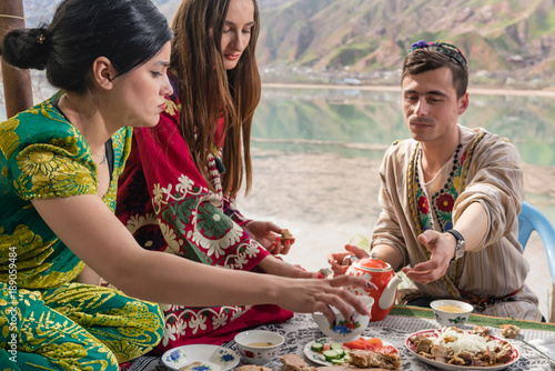 Group of Tajik women and men eating together in lakeside restaurant photo