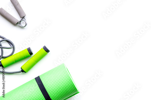 Do fintess in gym. Jump rope, expander and mat on white background top view copy space