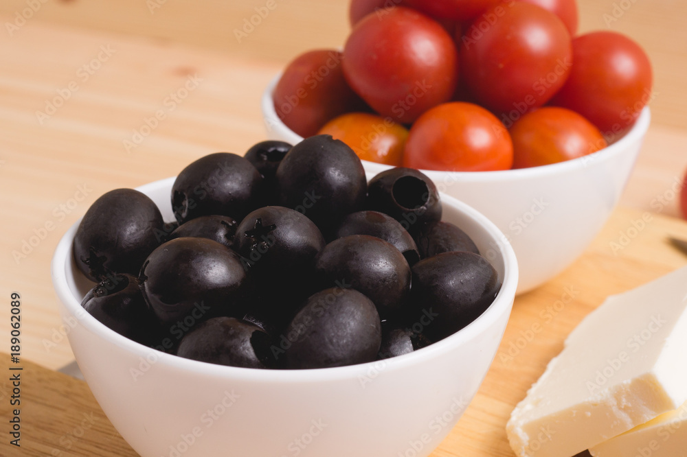 Greek salad with vegetables, feta cheese, black olives in process. Wooden background . Top view Greek salad with vegetables, feta cheese, black olives in process. Wooden background . Top view