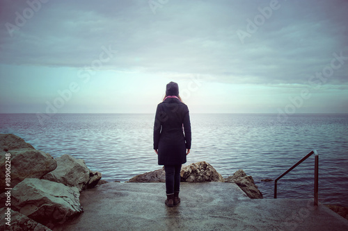 back view of lonely woman looking the see, loneliness concept in winter season