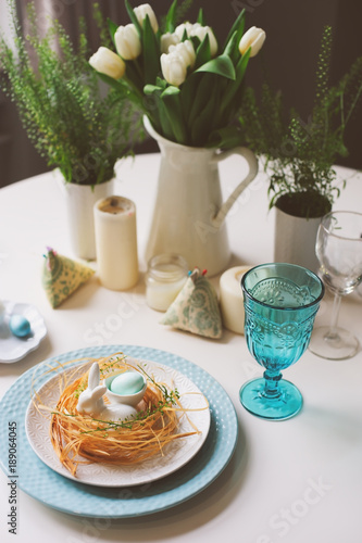 easter festive table with dining place decorated with nest, bunny and eggs