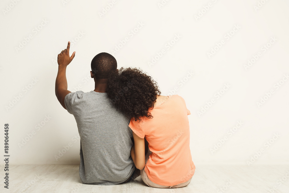 African-american couple looking up, sitting on floor African-american couple looking up, sitting on floor