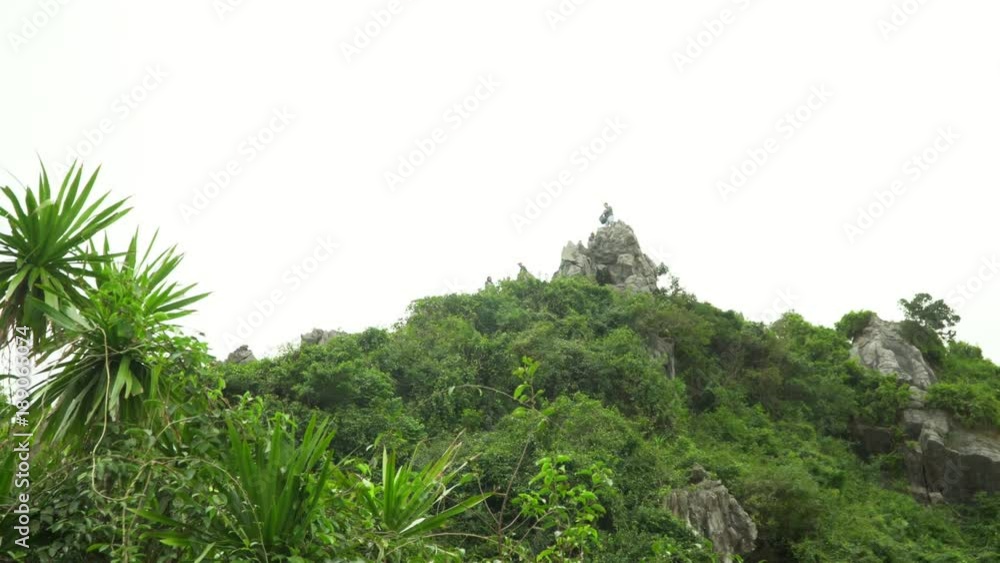 Tourists take the picture at rock top. A selfie at island top. A travel with backpacks. Island of monkeys. Tourists with backpacks. People at rock top. Vietnam Tourists take the picture at rock top. A selfie at island top. A travel with backpacks. Island of monkeys. Tourists with backpacks. People at rock top. Vietnam