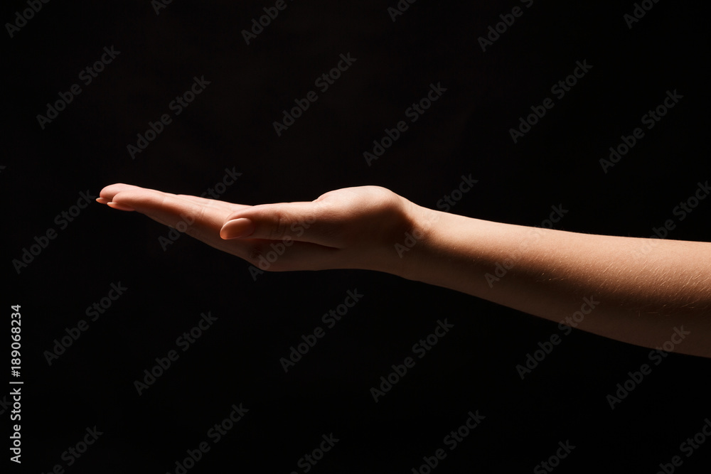 Woman holding palm open isolated on black