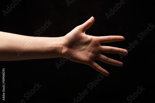 Female hand shows number five isolated at black