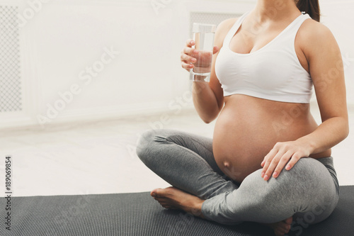 Unrecognizable pregnant woman drinking water