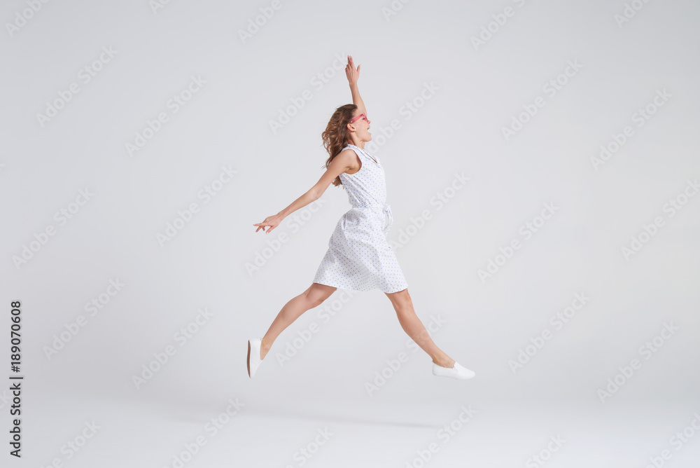 Fototapeta premium Pretty girl in dress jumping isolated over background
