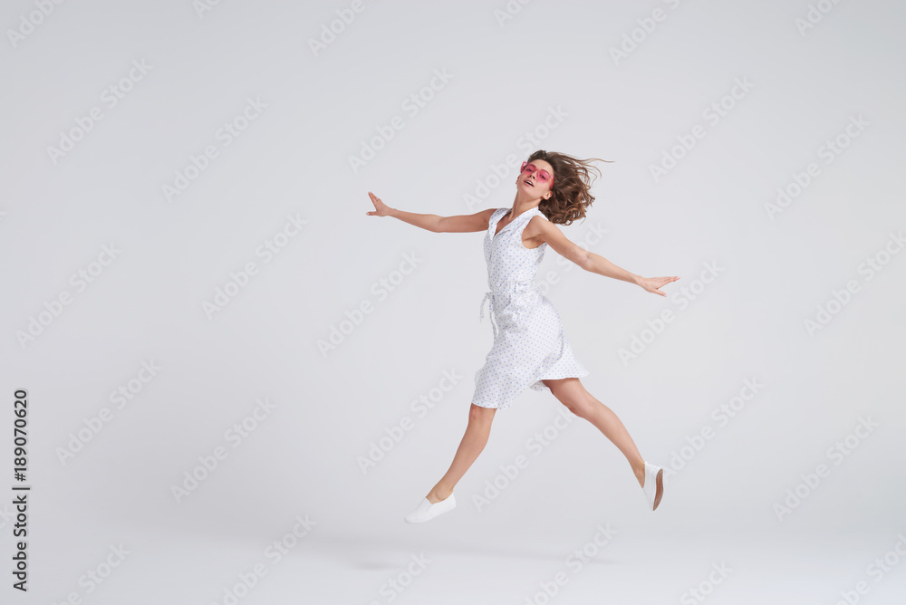 Cheerful girl jumping in air over white background