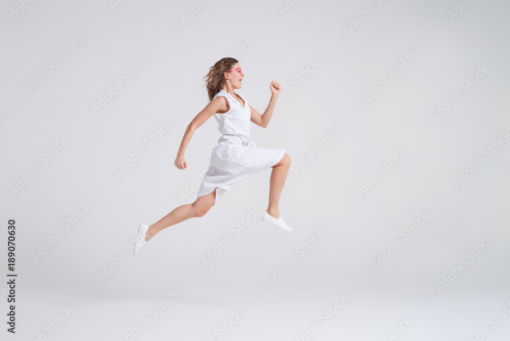 Fototapeta premium Crazy joyful girl in summer dress jumping isolated over background