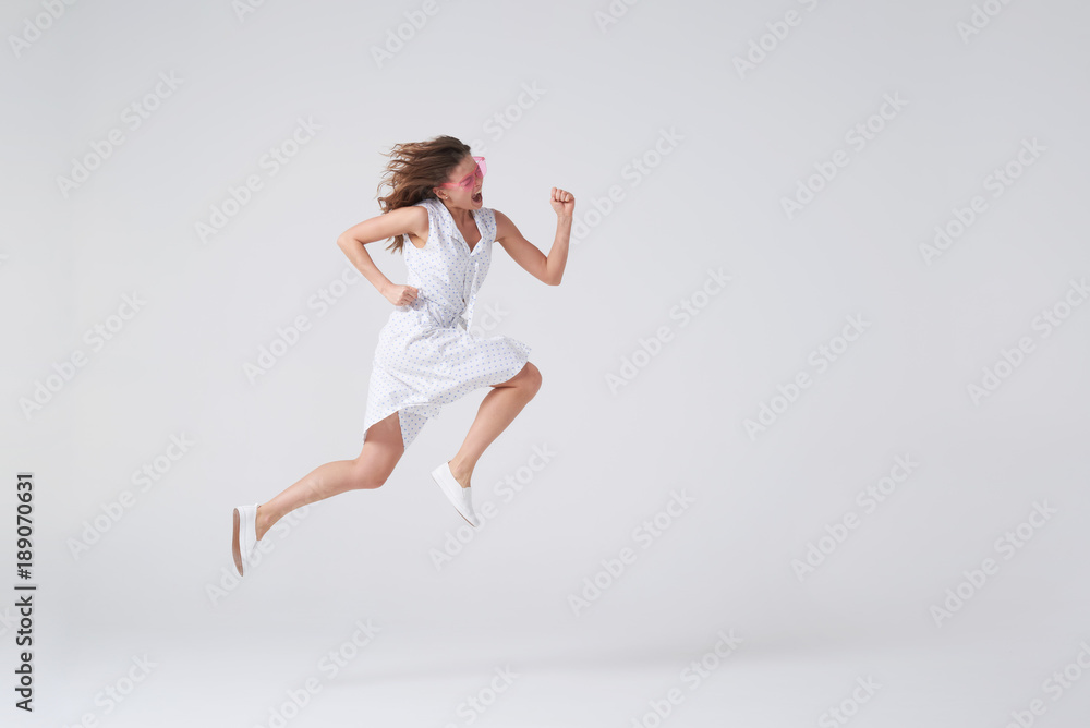 Joyous girl jumping up in air over background in studio