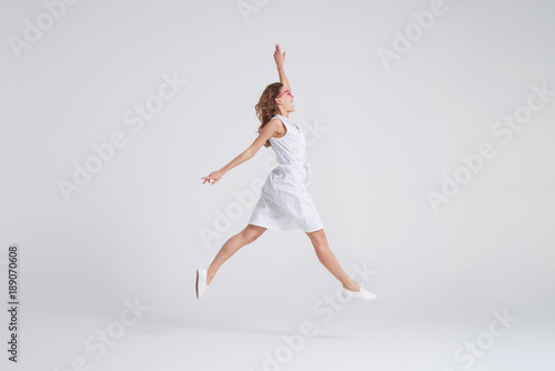 Pretty girl in dress jumping isolated over background